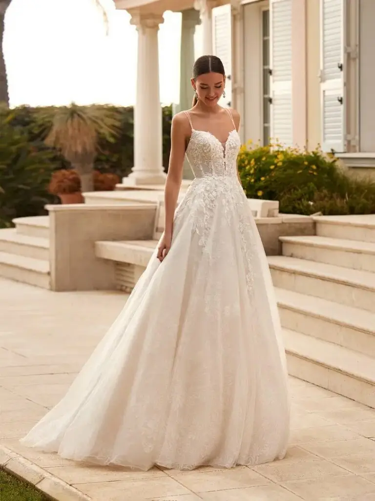 Brautkleid mit schmalen Trägern, floraler Spitze und weitem Rock vor einer Treppe