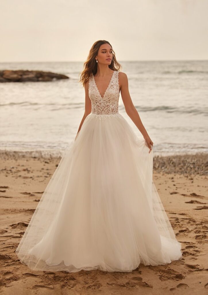 Brautkleid mit breiten Trägern, tiefem V-Ausschnitt und fließendem Rock am Strand