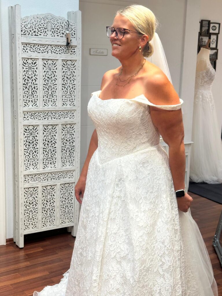 Lächelnde Braut im angepassten Spitzenkleid