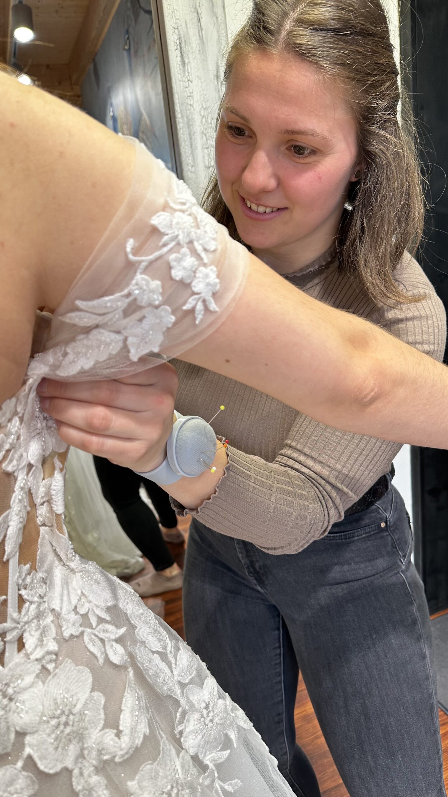 Schneiderin passt die Spitze eines Brautkleids sorgfältig an