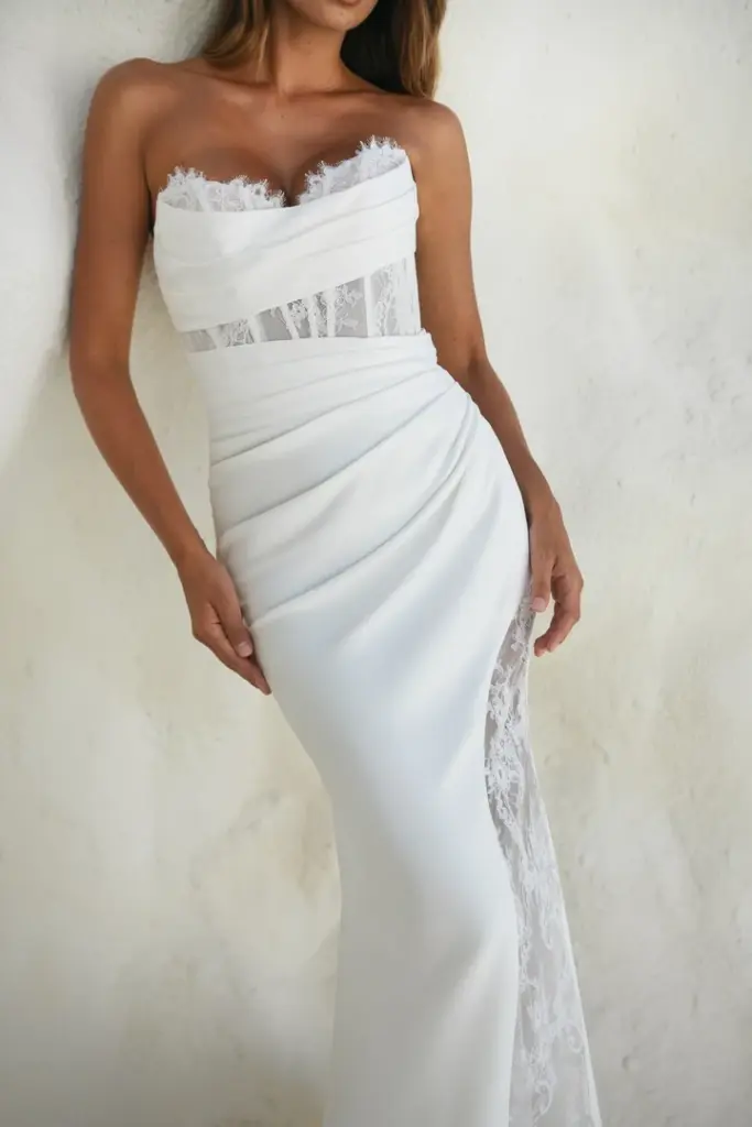 Detail eines trägerlosen Brautkleids mit drapiertem Stoff und transparentem Spitzeneinsatz