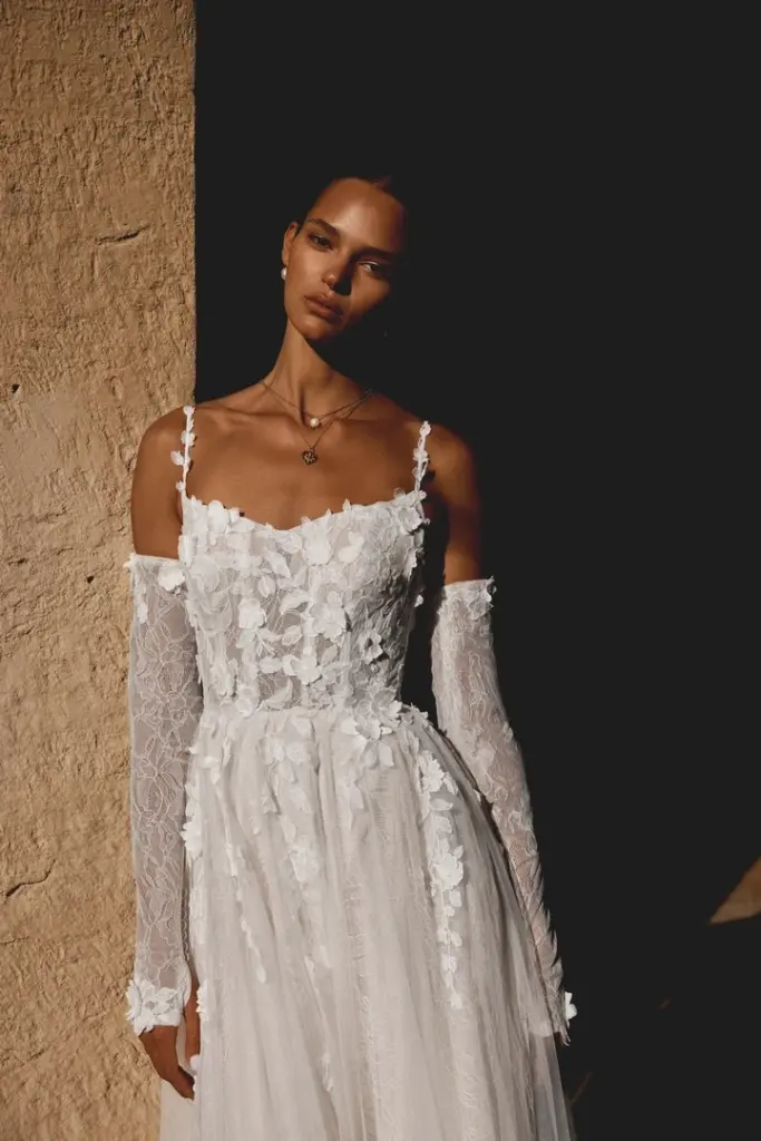 Brautkleid mit schmalen Trägern, langen Spitzenärmeln und floralen Applikationen
