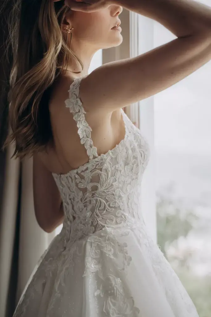 Seitliches Rückendetail eines Brautkleids mit floraler Spitze und breiten Trägern