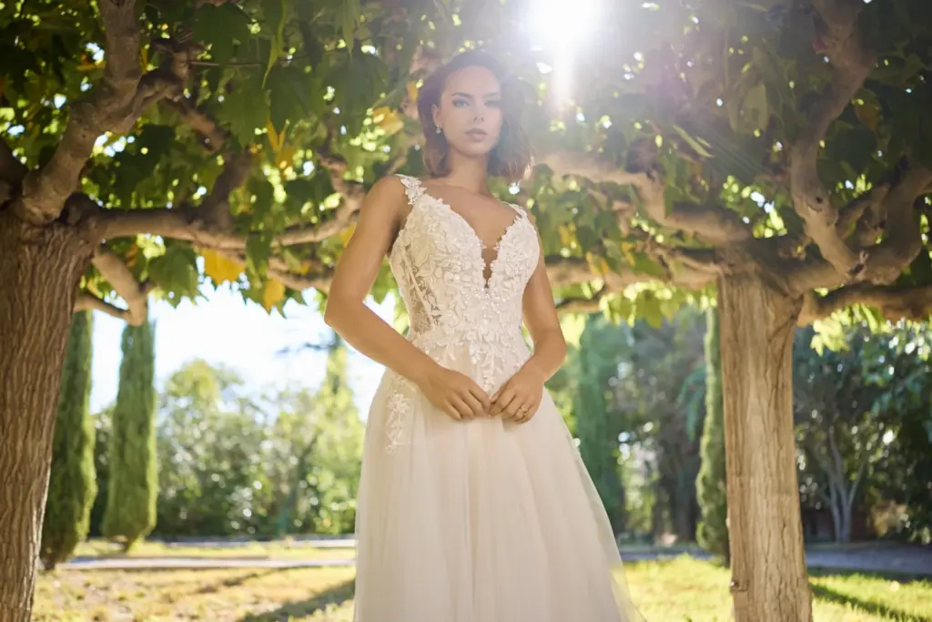 Brautkleid mit Spitzenoberteil und tiefem V-Ausschnitt unter einer Pergola